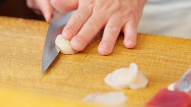 Deniz tarağı kesen bir suşi şefinin elleri.