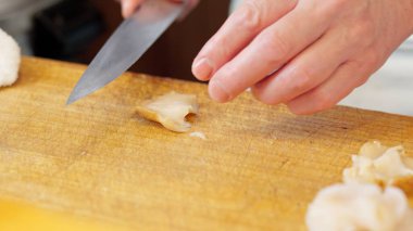 Bir suşi şefinin elleri bir eniği kesiyor.