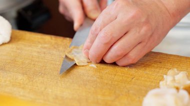 Bir suşi şefinin elleri bir eniği kesiyor.
