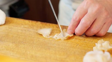 Bir suşi şefinin elleri bir eniği kesiyor.