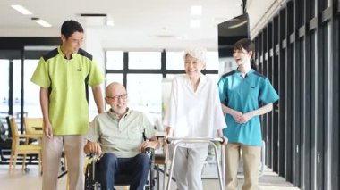 Asian caregiver supporting elderly people walking