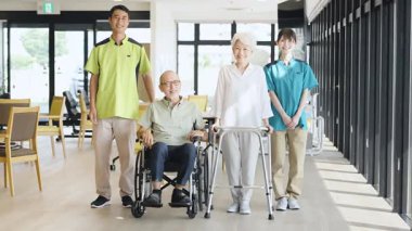 Asian caregiver supporting elderly people walking