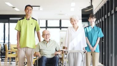 Asian caregiver supporting elderly people walking