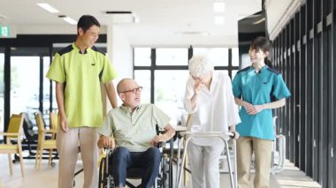 Asian caregiver supporting elderly people walking