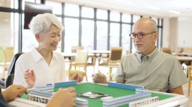 Asian elderly people playing mahjong in a care home
