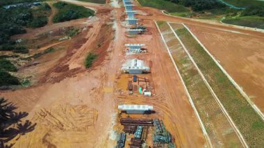 ECRL inşaat sahasının havadan 4K görüntüsü. Sütunları, kırmızı toprağı ve yakındaki trafiği var. Altyapı projeleri için ideal.
