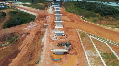 ECRL inşaat sahasının havadan 4K görüntüsü. Sütunları, kırmızı toprağı ve yakındaki trafiği var. Altyapı projeleri için ideal.