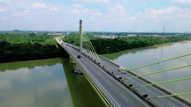 Dolambaçlı bir nehir manzarası ve yeşil orman ve kırsal kasaba manzarasıyla çevrili uzun bir köprü. Güzel doğa ve altyapı.