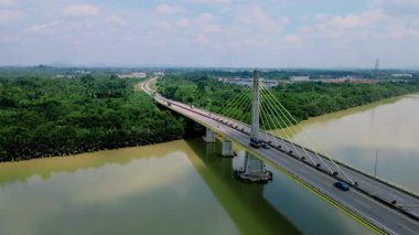 Dolambaçlı bir nehir manzarası ve yeşil orman ve kırsal kasaba manzarasıyla çevrili uzun bir köprü. Güzel doğa ve altyapı.