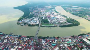 Nehirler, mangrov ormanları ve yerleşim alanlarıyla çevrili kıyı sanayi kasabasının geniş hava manzarası. Toprak ve su arasındaki stratejik yerleşim.