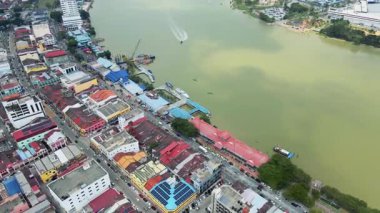 Malezya 'nın bir kasabasındaki renkli nehir kenarlı binaların hava manzarası. Tekneleri, çatıları ve etkin sokak manzaraları olan kentsel alan.