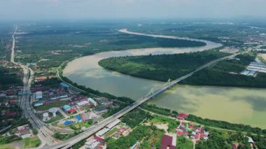 Dolambaçlı bir nehir manzarası ve yeşil orman ve kırsal kasaba manzarasıyla çevrili uzun bir köprü. Güzel doğa ve altyapı.