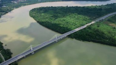Dolambaçlı bir nehir manzarası ve yeşil orman ve kırsal kasaba manzarasıyla çevrili uzun bir köprü. Güzel doğa ve altyapı.