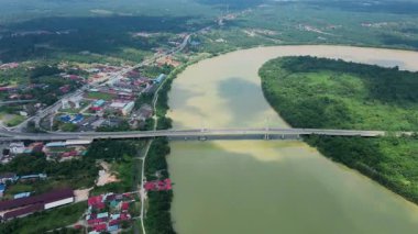 Dolambaçlı bir nehir manzarası ve yeşil orman ve kırsal kasaba manzarasıyla çevrili uzun bir köprü. Güzel doğa ve altyapı.