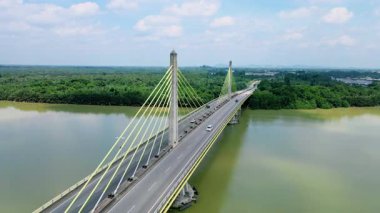 Dolambaçlı bir nehir manzarası ve yeşil orman ve kırsal kasaba manzarasıyla çevrili uzun bir köprü. Güzel doğa ve altyapı.