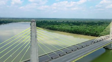 Dolambaçlı bir nehir manzarası ve yeşil orman ve kırsal kasaba manzarasıyla çevrili uzun bir köprü. Güzel doğa ve altyapı.