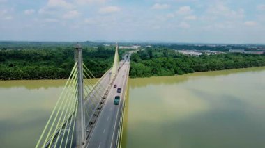 Dolambaçlı bir nehir manzarası ve yeşil orman ve kırsal kasaba manzarasıyla çevrili uzun bir köprü. Güzel doğa ve altyapı.