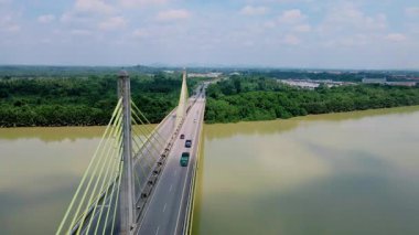 Dolambaçlı bir nehir manzarası ve yeşil orman ve kırsal kasaba manzarasıyla çevrili uzun bir köprü. Güzel doğa ve altyapı.