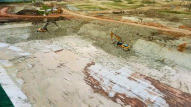 Shah Alam, Selangor, Malezya - 16 Mart 2025 - Çamurlu bir arazide kazı yapan iki kazıcının yer aldığı bir inşaat alanının havadan görünüşü.