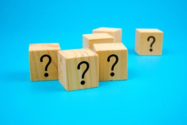 Wooden cubes with printed question mark symbols on blue background, symbolizing curiosity, doubt, confusion, decision making, problem solving, or brainstorming concept. Ideal for business, education, and creativity themes.
