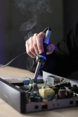 Eski bir uydu ayarlayıcısının masadaki kişi tarafından onarılması ve gri arka plan