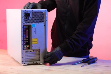 Masadaki bir kişi tarafından eski bir masaüstü bilgisayarının sökülmesi ve pembe arkaplan