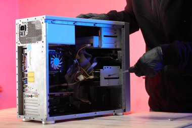 Masadaki bir kişi tarafından eski bir masaüstü bilgisayarının sökülmesi ve pembe arkaplan