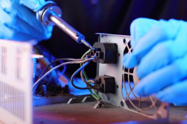 bir masadaki bilgisayar güç kaynağının bir kişi tarafından sökülmesi ve pembe bir arka plan