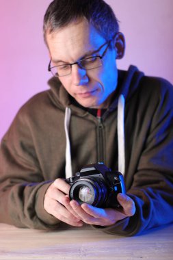 Elleri masa ve renkli arkaplanda eski manuel lensli dijital kamera