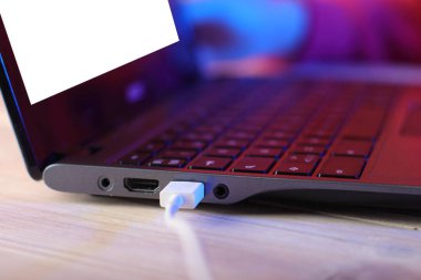 Masasında USB kablosu ve pembe arka planı olan eski dizüstü bilgisayar