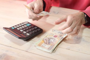 Tablo ve renkli arkaplanda hesap makinesi olan cila zloti banknotlarını saymak