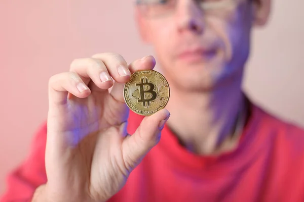 Renkli bir arka planda, sağ elinde bozuk para tutan bir adam.