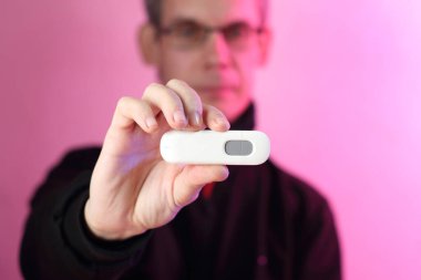 Pembe arka planda siyah bir sweatshirt giyen birinin elindeki gsm modemi.