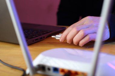 Pembe arka planda siyah sweatshirt giyen biri tarafından bilgisayara gsm modemi yerleştiriliyor.