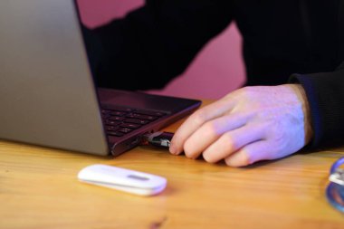 Siyah kazaklı birinin arka planına karşı dizüstü bilgisayara yerleştirilen siyah gsm modemi.