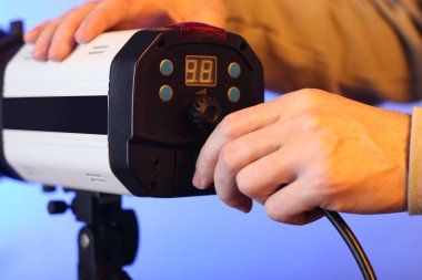 Arka planda bir kişi stüdyonun flaşına güç kablosu yerleştiriyor.