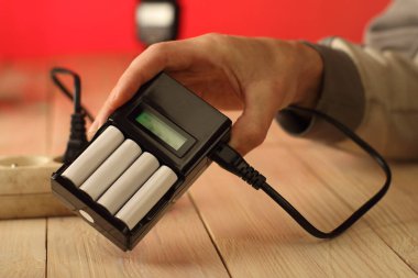 charger with batteries in a person's hand on a colored background