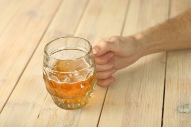 mug of beer in hand over plank table