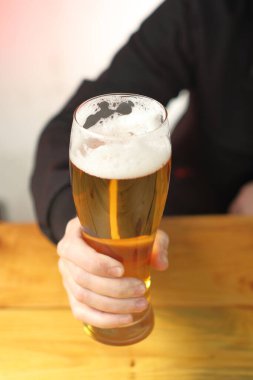 mug with beer in hand on the table and the background of the person