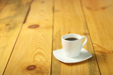 Tahta bir masada beyaz bir fincan kahve.