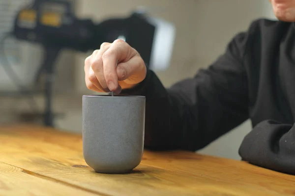 person mixing coffee in a mug on a wooden table