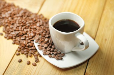 cup with coffee on a wooden table with coffee beans