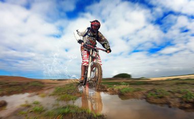 Yağmurdan sonra okyanus kıyısında kırmızı kasklı bir bisikletçi.