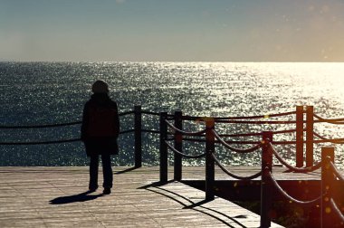 The silhouette of a woman on a pontoon in the sunlight