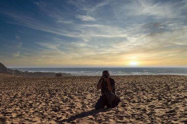Akşamın sonunda sahilde bir fotoğrafçı.