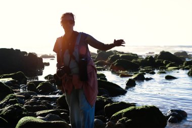 Okyanusun kenarında fotoğraf çeken bir kadın.