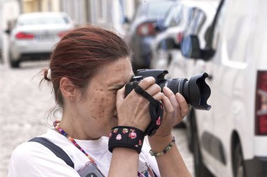 Okyanusun kenarında kamerası olan kızıl saçlı kadın.