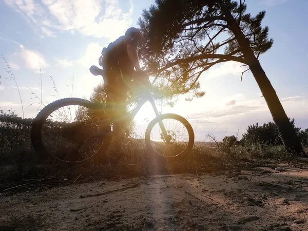 一个骑自行车的人日落时戴着红色头盔骑自行车 — 图库照片