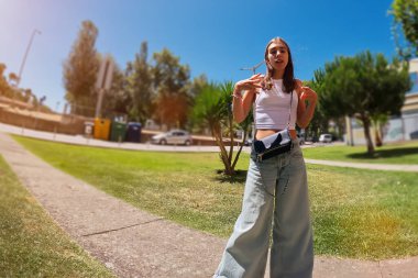 Genç ve güzel bir kadın güneşli bir yaz gününde parkta yürüyor..