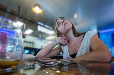 Genç bir kadın bir barda oturuyor ve bakıyor..